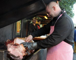 The hams rotate slowing over a wood fire.